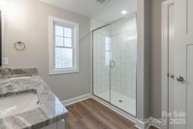 full bath with wood finished floors, a sink, visible vents, baseboards, and double vanity