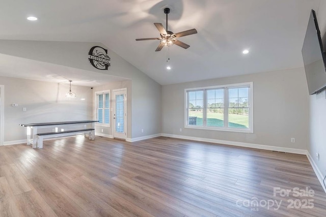 unfurnished living room featuring vaulted ceiling, light wood finished floors, and baseboards