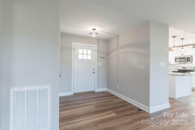 entryway featuring visible vents, baseboards, and wood finished floors