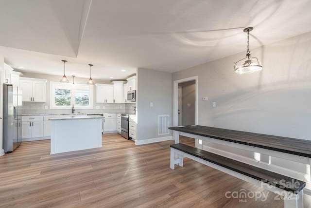 kitchen featuring appliances with stainless steel finishes, light countertops, decorative light fixtures, and white cabinetry