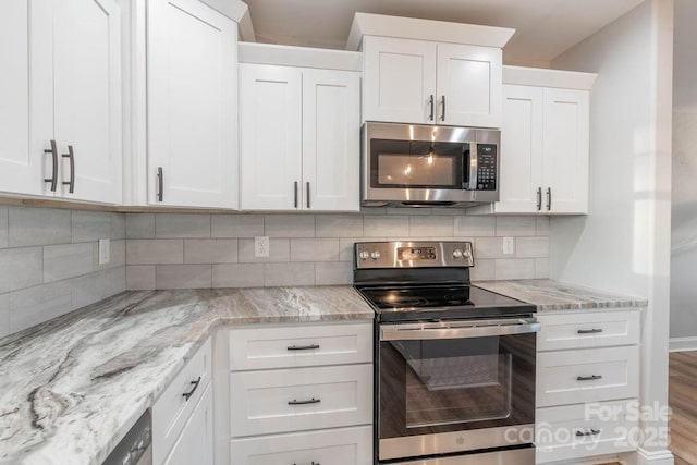 kitchen with appliances with stainless steel finishes, white cabinets, decorative backsplash, and wood finished floors