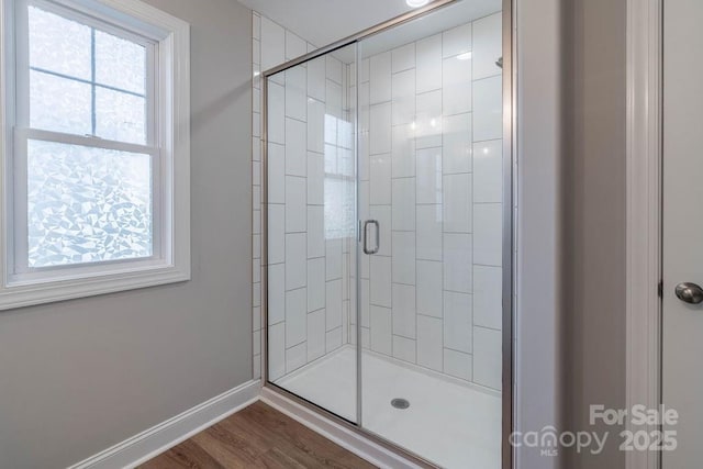 bathroom with a stall shower, plenty of natural light, wood finished floors, and baseboards