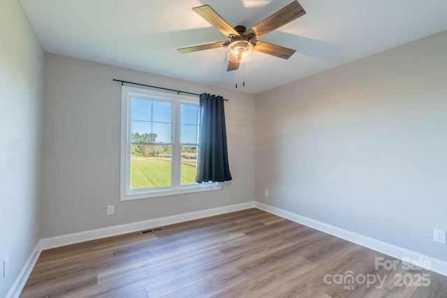 unfurnished room featuring visible vents, baseboards, and wood finished floors