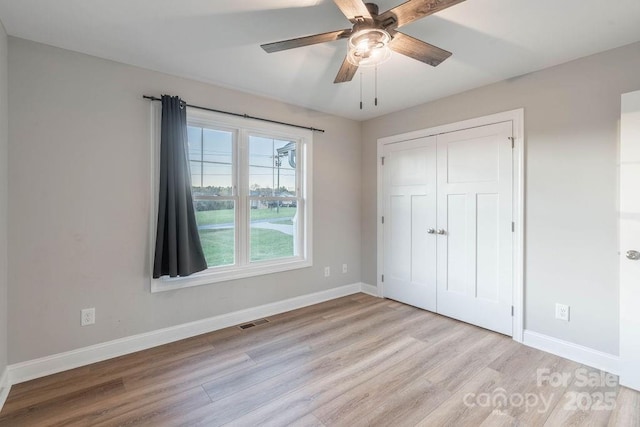 unfurnished bedroom featuring light wood-style floors, baseboards, visible vents, and a closet