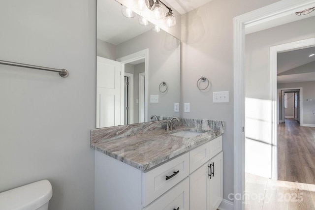 bathroom featuring toilet, wood finished floors, vanity, and baseboards