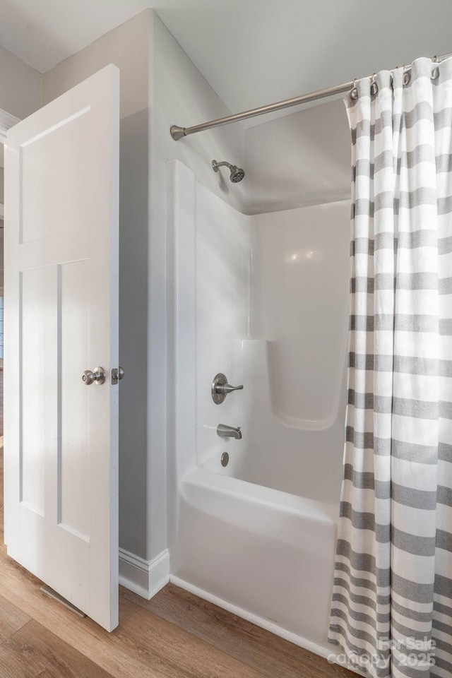 bathroom featuring wood finished floors and shower / tub combo with curtain