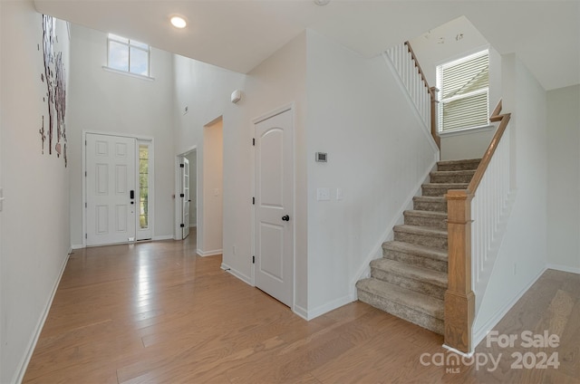 entrance foyer with a towering ceiling and light hardwood / wood-style flooring