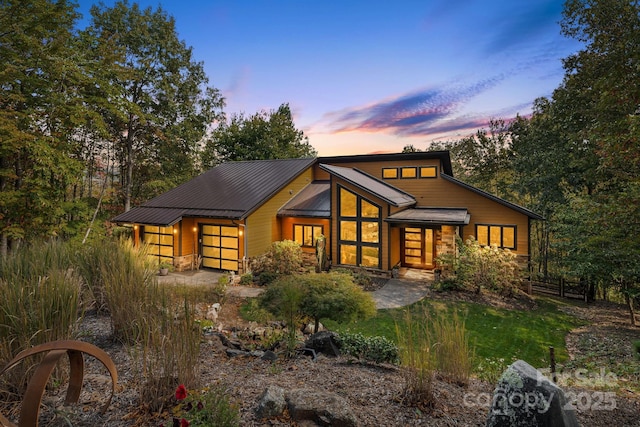 view of front of property with an attached garage, stone siding, and metal roof