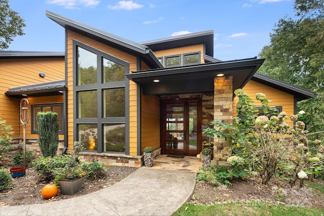 property entrance featuring stone siding and french doors