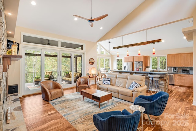 living room with light hardwood / wood-style flooring, high vaulted ceiling, french doors, and ceiling fan