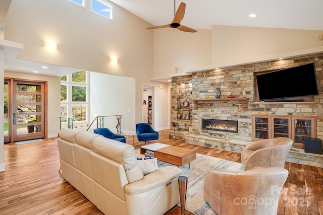 living room featuring plenty of natural light, light wood-style flooring, and a stone fireplace