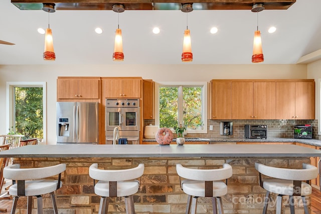 kitchen with tasteful backsplash, hanging light fixtures, a breakfast bar area, and appliances with stainless steel finishes