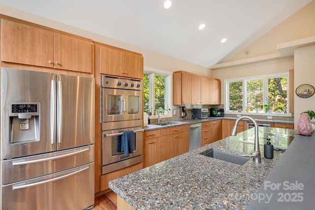 kitchen featuring sink, dark stone counters, and appliances with stainless steel finishes