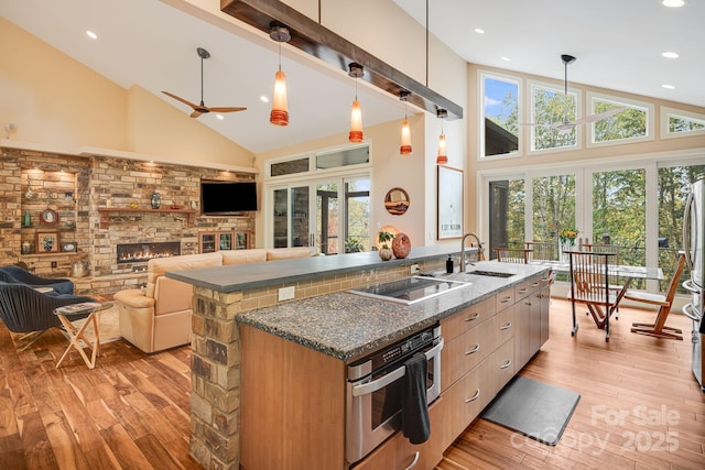 kitchen with dark stone counters, hanging light fixtures, black electric stovetop, stainless steel oven, and ceiling fan