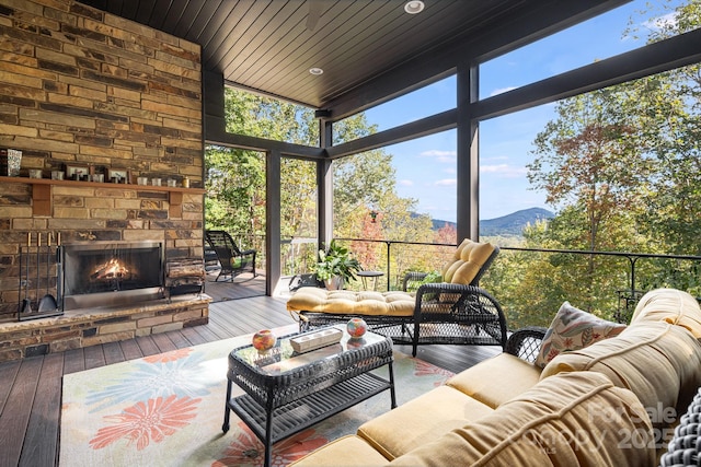 sunroom featuring wood ceiling, an outdoor stone fireplace, and a mountain view