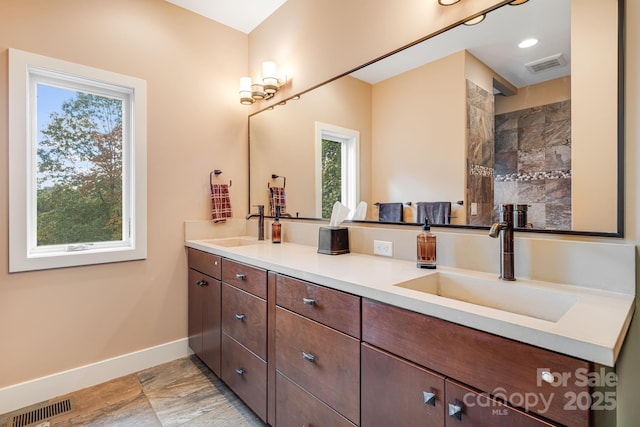 bathroom featuring double vanity, baseboards, visible vents, and a sink