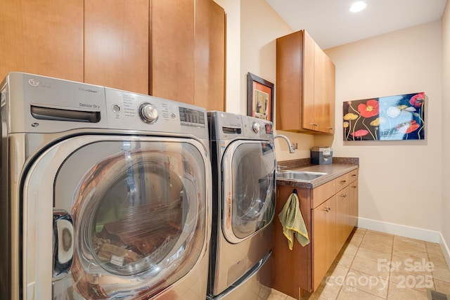 washroom featuring cabinet space, light tile patterned floors, baseboards, separate washer and dryer, and a sink