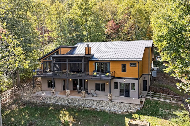 back of property featuring metal roof, a patio, fence, a sunroom, and a standing seam roof