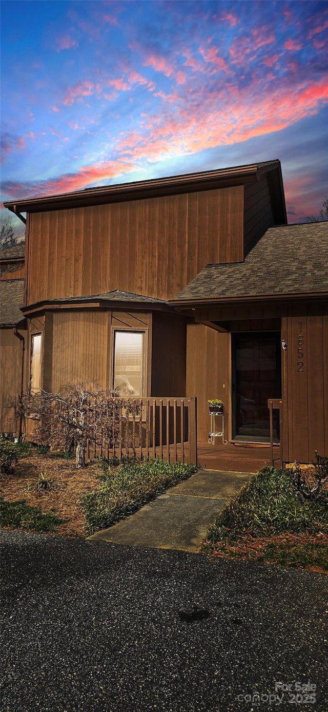 view of side of property with a shingled roof and covered porch