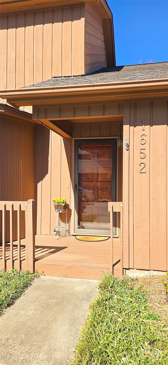 entrance to property featuring a shingled roof and board and batten siding