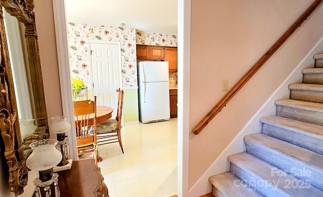 stairway with tile patterned floors and wallpapered walls