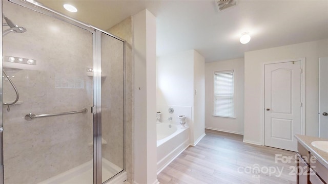 bathroom featuring hardwood / wood-style floors, vanity, and plus walk in shower