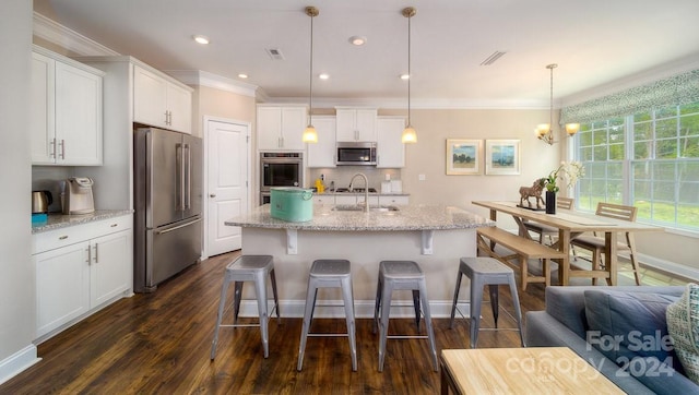 kitchen with an island with sink, white cabinetry, stainless steel appliances, decorative light fixtures, and dark hardwood / wood-style floors