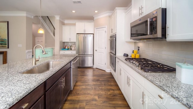 kitchen featuring dark wood-type flooring, stainless steel appliances, sink, pendant lighting, and white cabinets