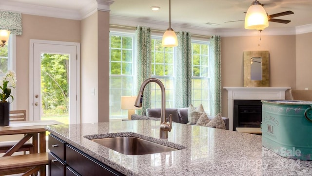 kitchen featuring sink, light stone countertops, decorative light fixtures, and a healthy amount of sunlight