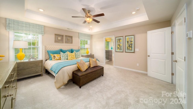 carpeted bedroom with ceiling fan, a raised ceiling, and ensuite bath