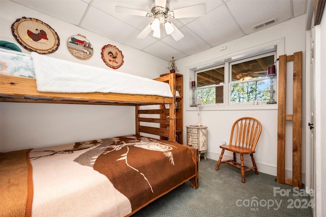 carpeted bedroom with a paneled ceiling and ceiling fan