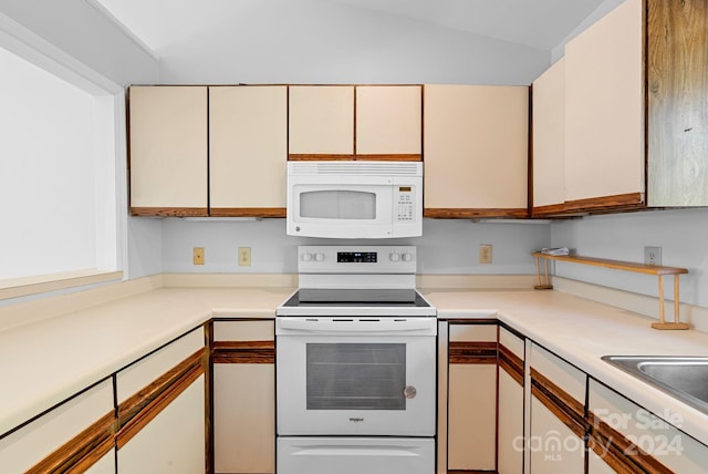 kitchen with white appliances, vaulted ceiling, and sink