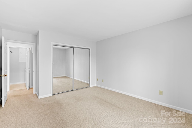 unfurnished bedroom with light colored carpet and a closet