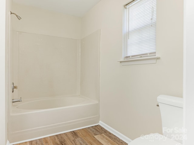 bathroom with toilet, wood-type flooring, and tub / shower combination