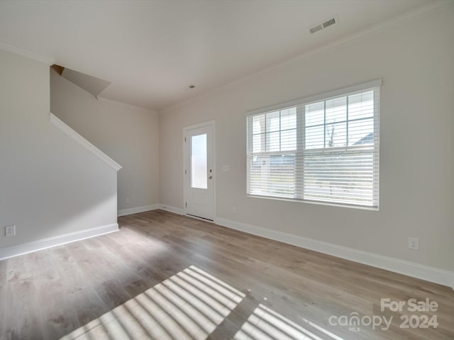 entrance foyer with ornamental molding and light hardwood / wood-style floors