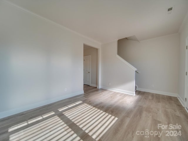 unfurnished room featuring light wood-type flooring and crown molding