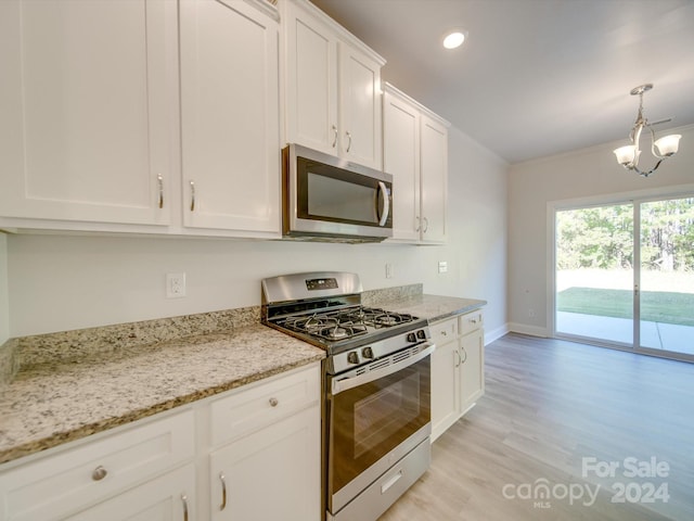 kitchen featuring white cabinets, light stone countertops, light wood-type flooring, appliances with stainless steel finishes, and decorative light fixtures