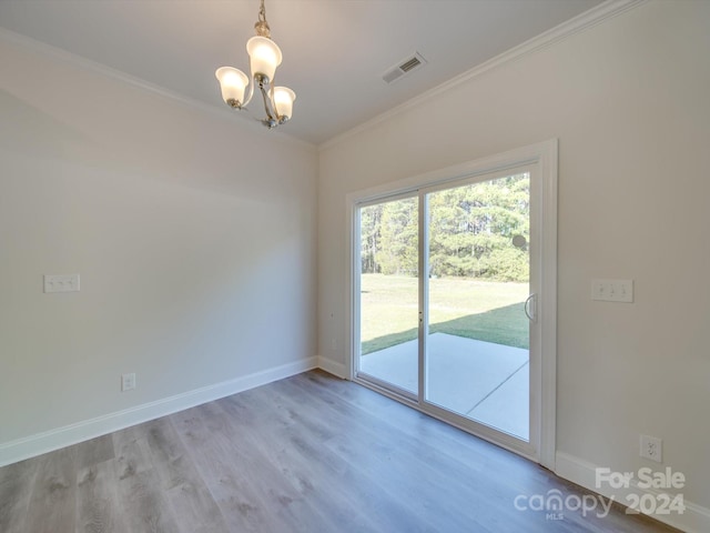 spare room featuring an inviting chandelier, light hardwood / wood-style floors, and crown molding