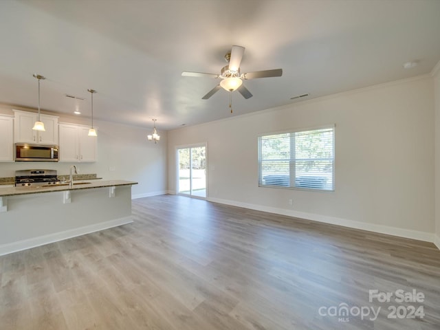 kitchen featuring plenty of natural light, white cabinetry, decorative light fixtures, and stainless steel appliances