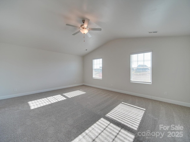 carpeted spare room featuring visible vents, vaulted ceiling, baseboards, and ceiling fan