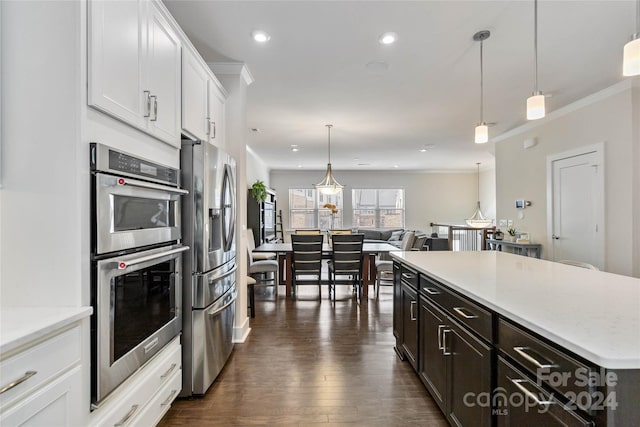 kitchen featuring appliances with stainless steel finishes, pendant lighting, white cabinetry, and dark hardwood / wood-style flooring