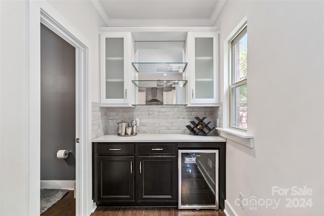 bar featuring decorative backsplash, dark wood-type flooring, wine cooler, ornamental molding, and dark brown cabinetry