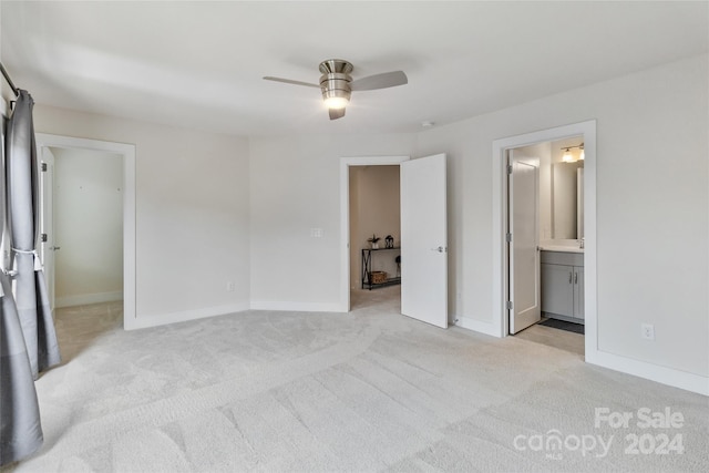 unfurnished bedroom featuring ensuite bathroom, light colored carpet, and ceiling fan