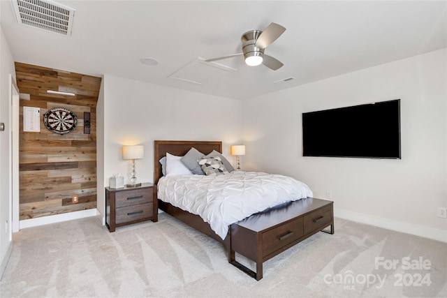 bedroom with light carpet, wooden walls, and ceiling fan