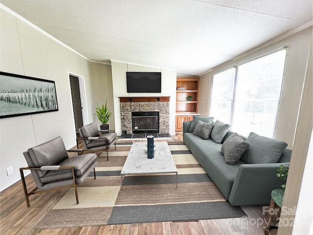 living room featuring wood finished floors, ornamental molding, a fireplace, and built in shelves