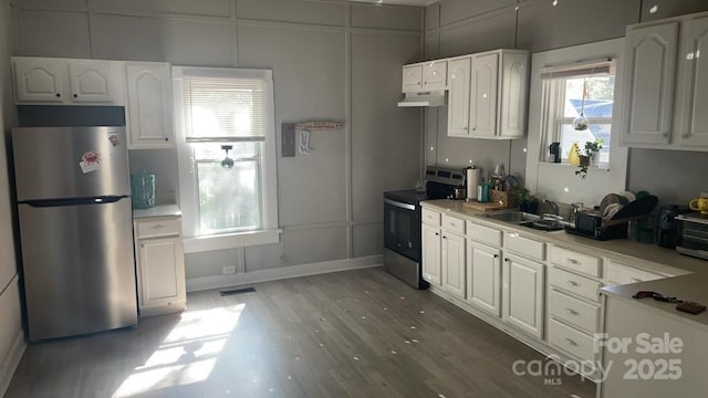 kitchen featuring sink, stainless steel appliances, white cabinetry, and wood-type flooring