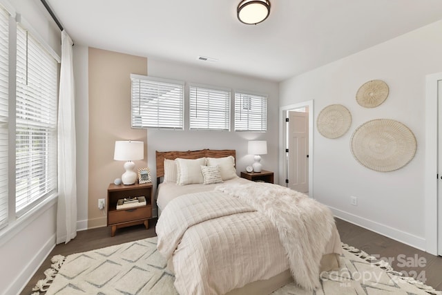 bedroom with multiple windows and dark hardwood / wood-style flooring