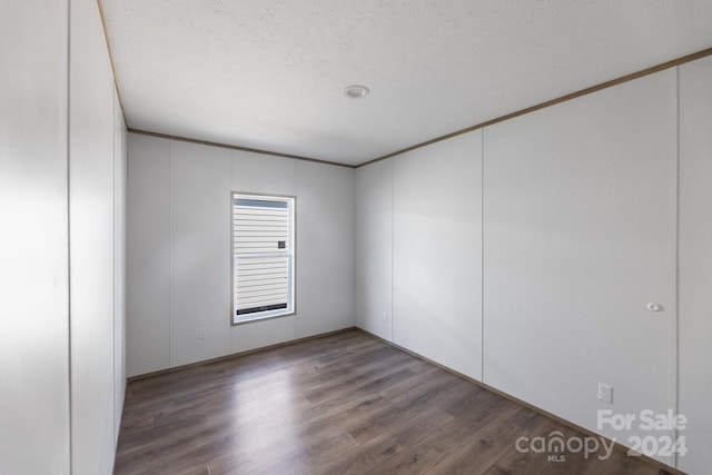 unfurnished room with ornamental molding, dark wood-type flooring, and a textured ceiling