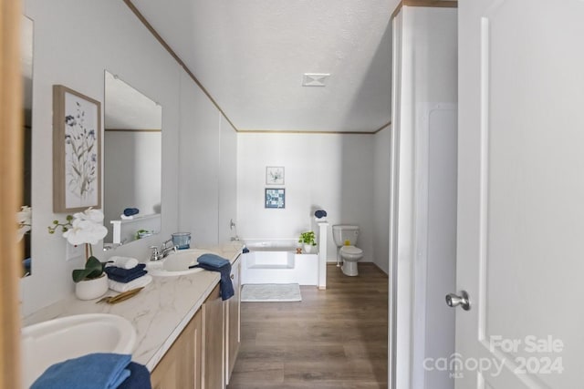 bathroom with toilet, a textured ceiling, hardwood / wood-style flooring, a bathtub, and vanity