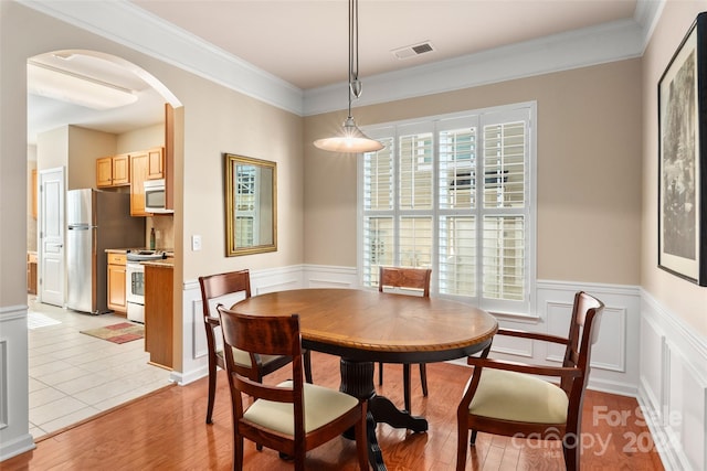 dining area featuring crown molding, plenty of natural light, and light wood-type flooring